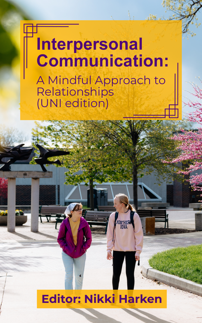 two college students walking on the UNI campus, outside Maucker Union with spring trees in the background