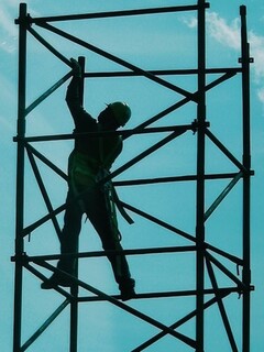 A worker stands on metal scaffolding to make repairs.