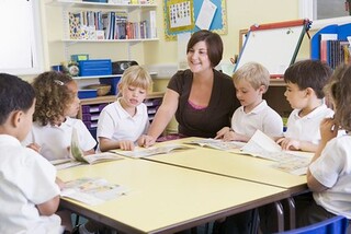 A teacher works with students at a table