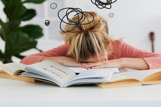 A young lady with her head down. Black swirls are drawn to show frustration.
