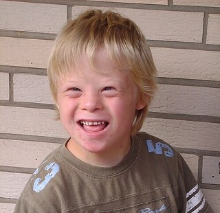A smiling 8-year-old boy with Down Syndrome